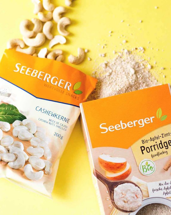Seeberger Bio-Apfel-Zimt-Porridge und Seeberger Cashewkerne auf gelber Platte