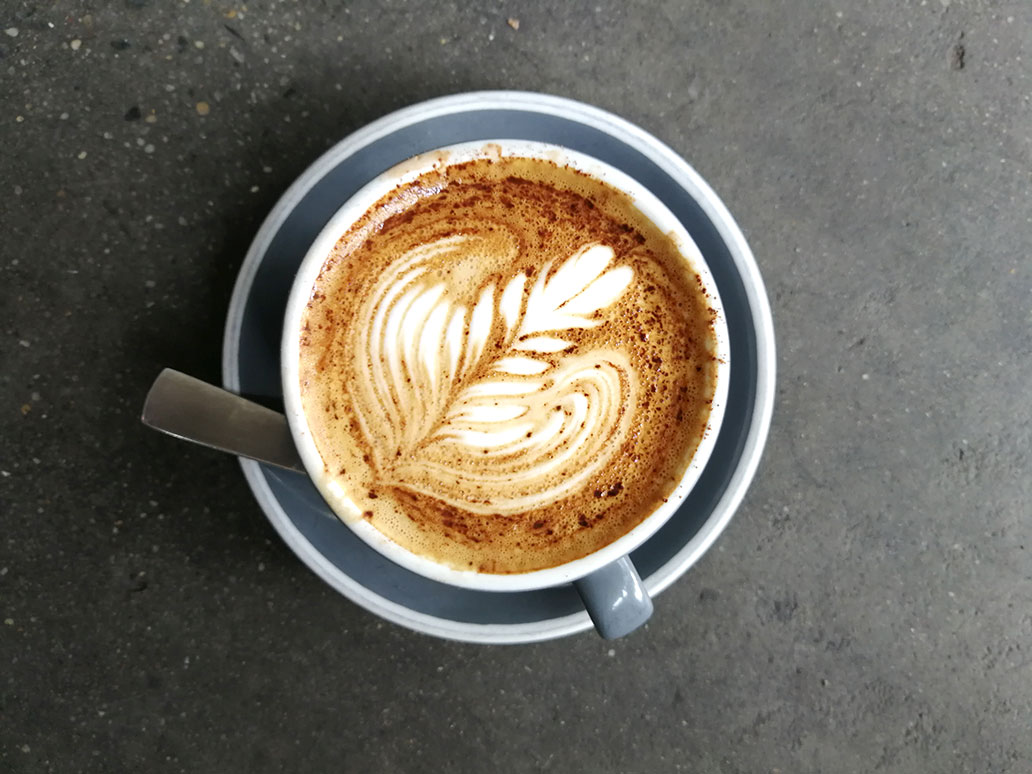 [Translate to Français:] Latte Art in Kaffeetasse auf Holztisch
