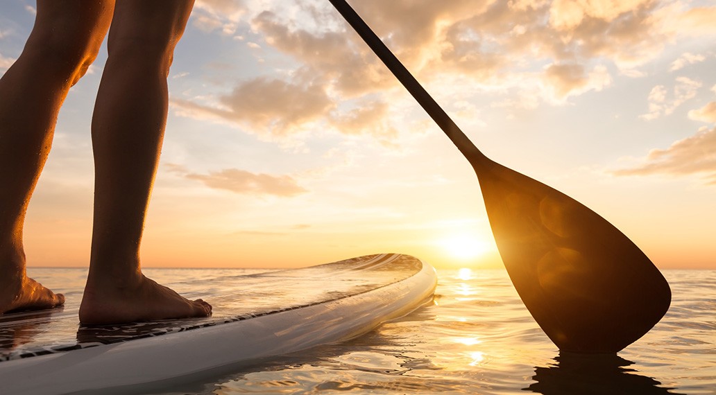 [Translate to Français:] Nahaufnahme Frau steht auf Stand Up Paddle Board während Sonnenuntergang