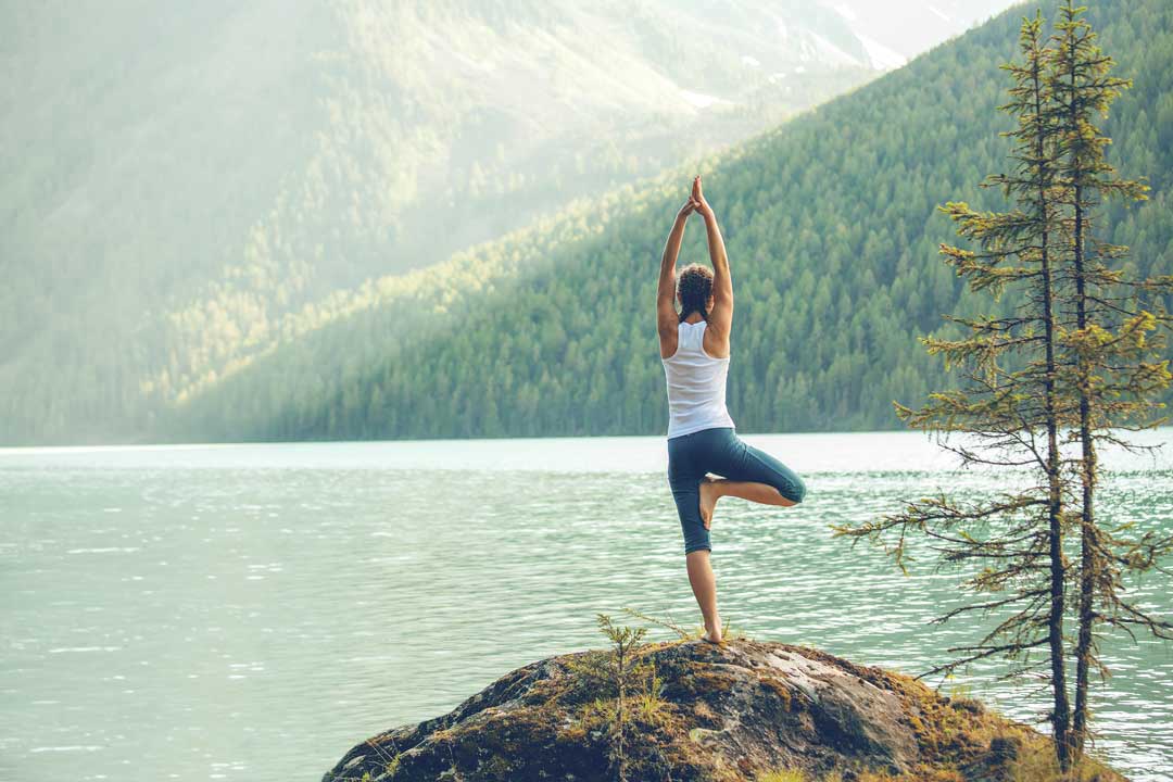Frau macht Yoga vor einer Bergkulisse.