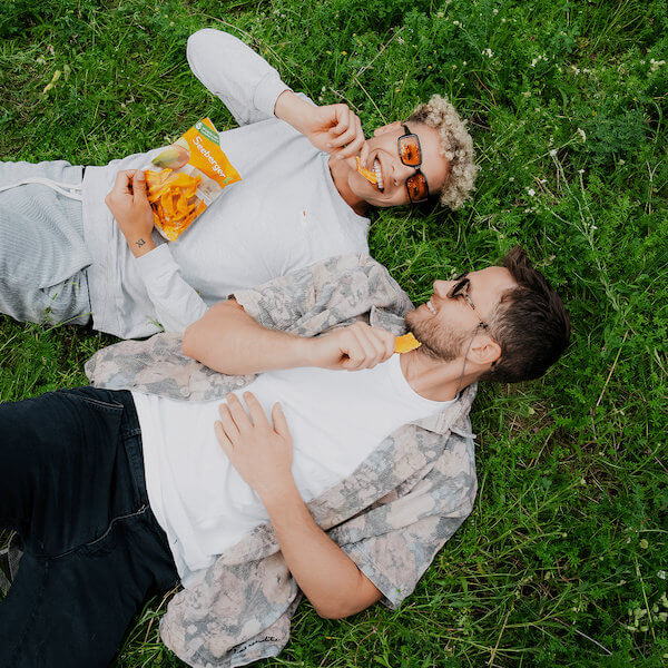 Zwei junge Männer liegen im Gras und snacken Seeberger Mangos